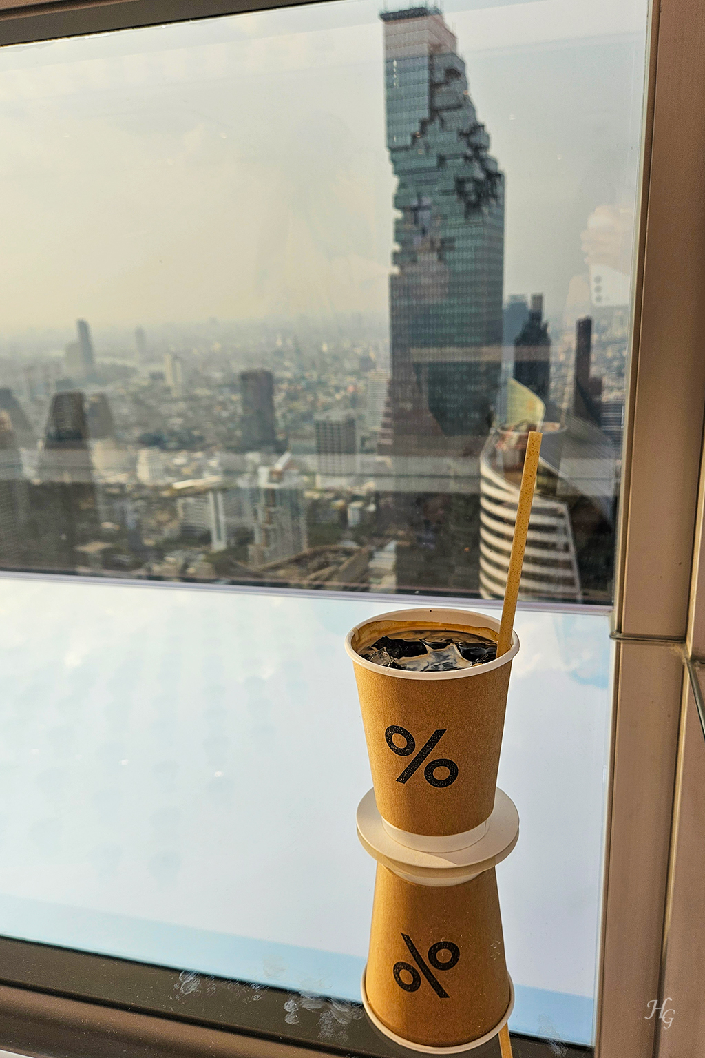 응커피 컵에 담긴 커피와 유리창 너머 보이는 마하나콘 건물