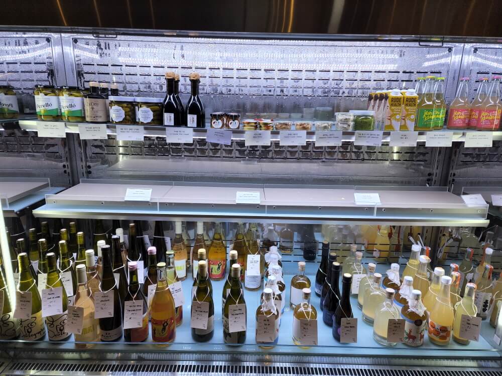 플링크에서 판매하고 있는 식료품들.각종 음료&#44; 올리브&#44; 비네거&#44; 앤쵸비&#44; 와인들이 냉장고 안에 진열되어 있다.