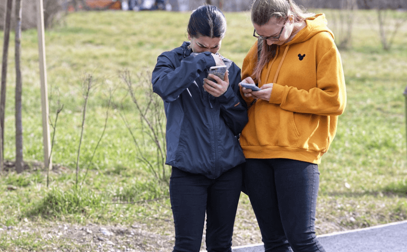 두명의 여자가 휴대폰을 들고 무엇인가를 하고 있다