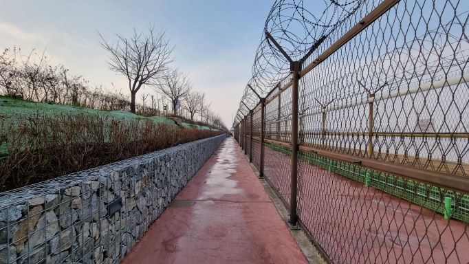 왼쪽 둑방 위는 자전거길&#44; 가운데 새로 개방된 길&#44; 우측에 이중으로 쳐진 철책선&#44; 가운데 철책선은 철거되고 일부 남겨둔 구간&#44;