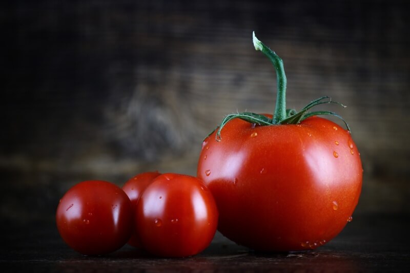 빨갛게 잘 익은 큰 토마토 1 개와 작은 토마토 3 개가 있는 사진