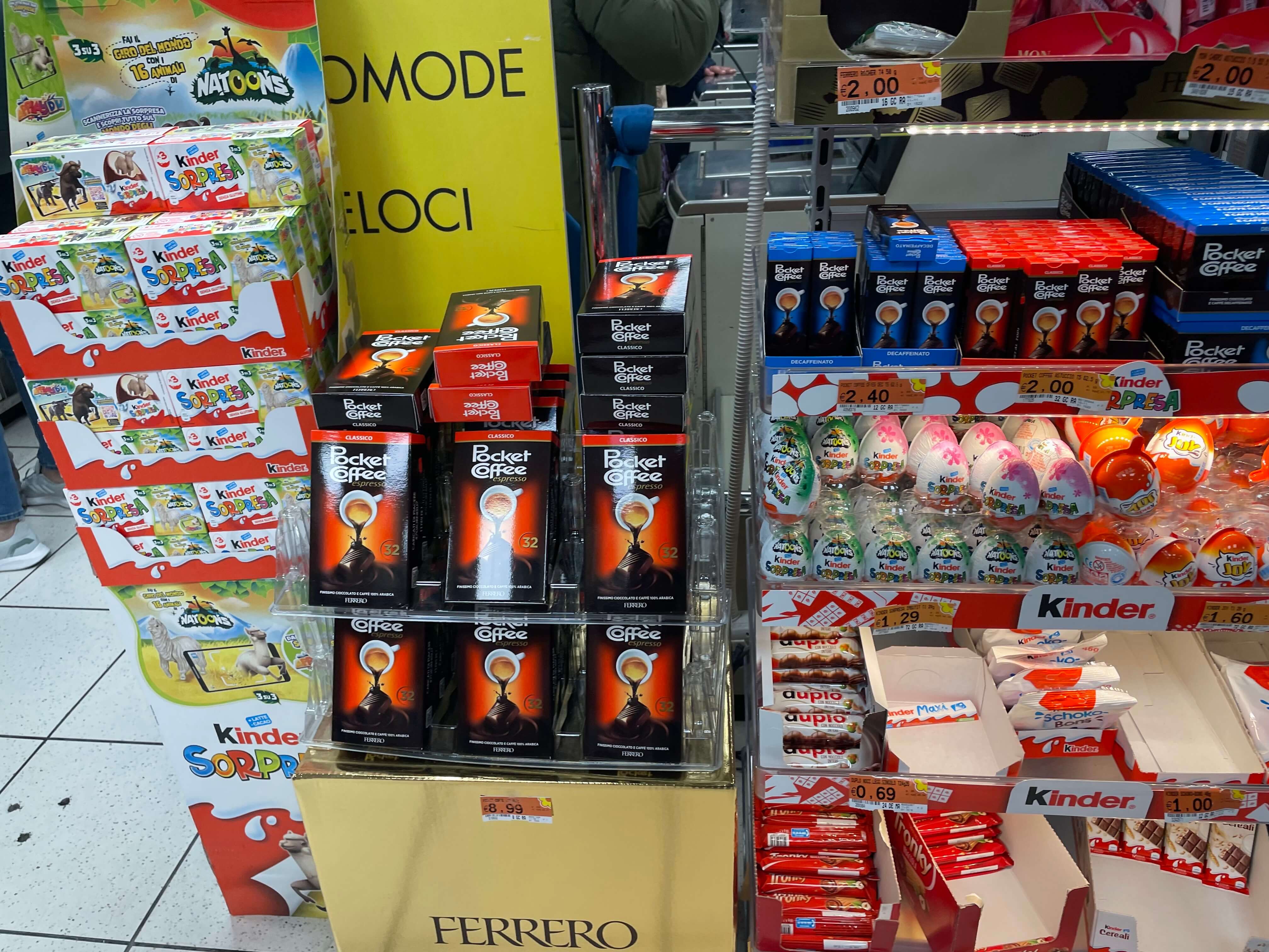 슈퍼마켓진열대모습. 여러 초콜릿들과 다른 스낵들이 진열대에 있는 모습. 오리지널 포켓커피 빨간색 박스가 진열대에 있는 모습.