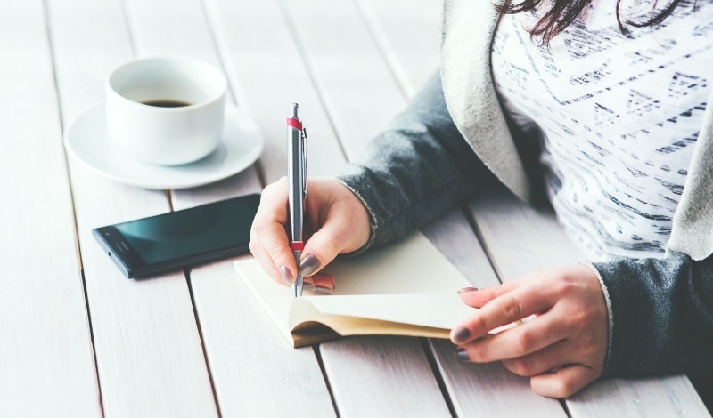 A female international student writing notes about U.S. visa procedures after deciding to take a break from studies