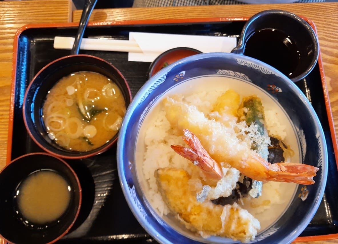 접시위에 밥이 놓여져 있고 그 위로 새우튀김과 다른 튀김들이 올려져 있다. 옆으로는 일본의 된장찌개인 미소시루가 같이 놓여져 있다.