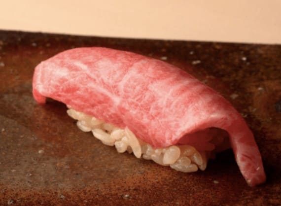 붉은 색의 생선이 올라가 있는 스시가 접시위에 올려져 있다