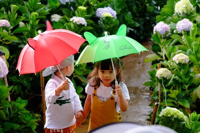 우산을 여자아이와 남자아이가 손잡고 걷는 모습