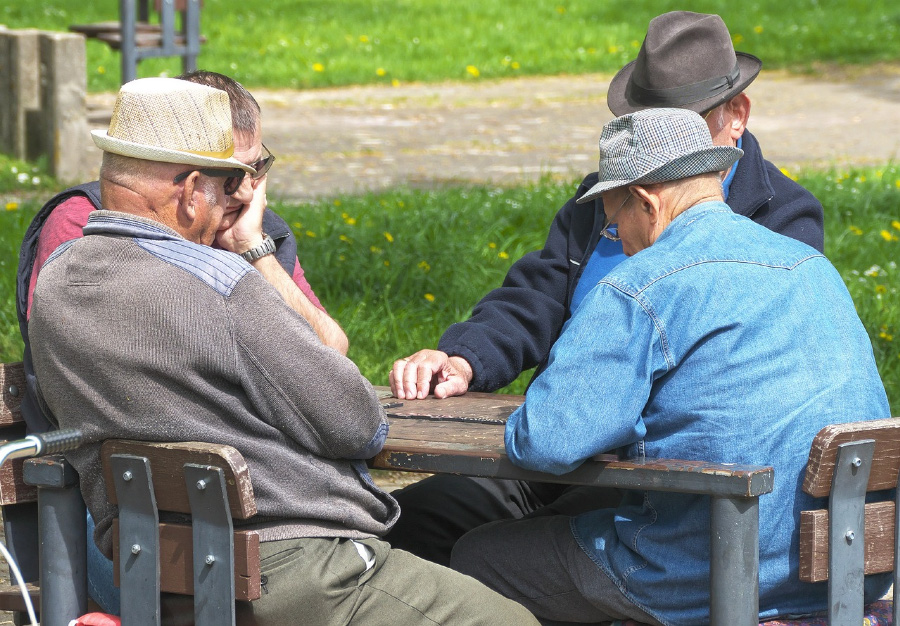 장수촌에서 사시는 노인 4분이 테이블에 서로 마주보고 앉아서 보드게임을 하고 있는 모습을 찍은 사진