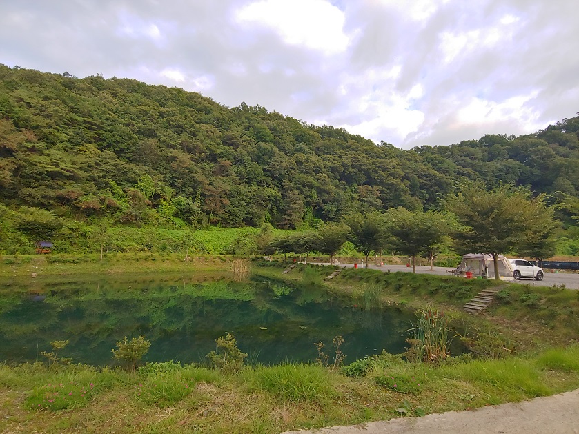 산과-나무가-있는-저수지-옆에-텐트-하나