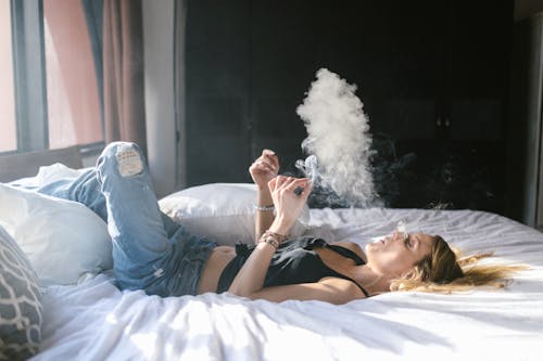 침대에서 담배를 피우고 있는 여성 모습