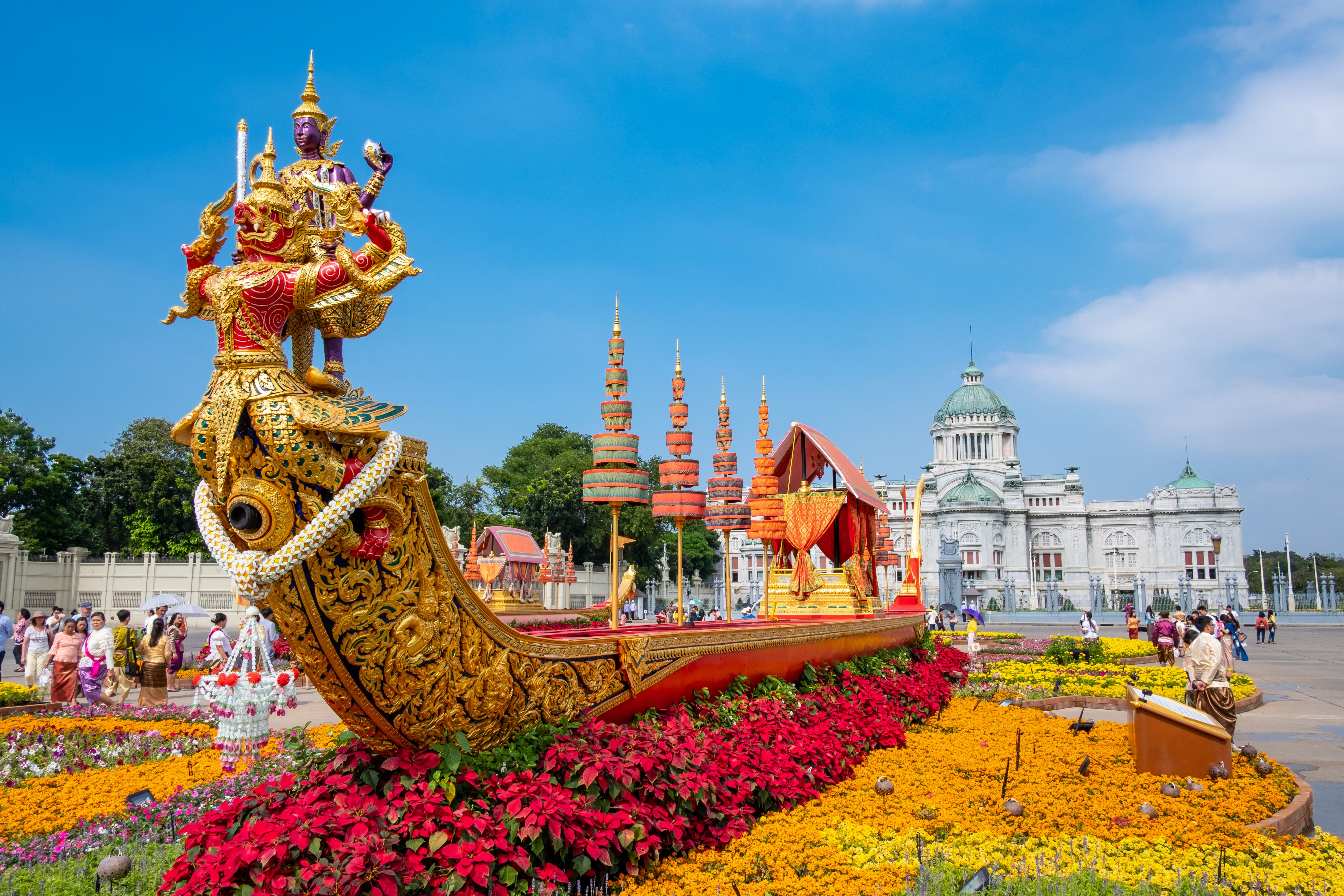 태국 방콕의 한 사원과 그 앞에 꽃과 화려한 신상으로 꾸며진 사원의 정원 모습