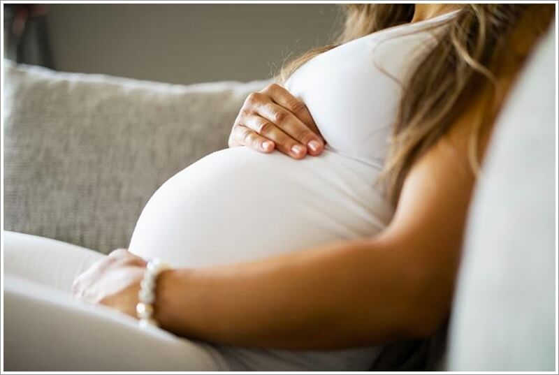 소파에 앉아 있는 임신 중인 여성