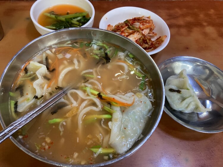 칼국수와 만두&#44; 걷절이와 열무김치가 있는 사진