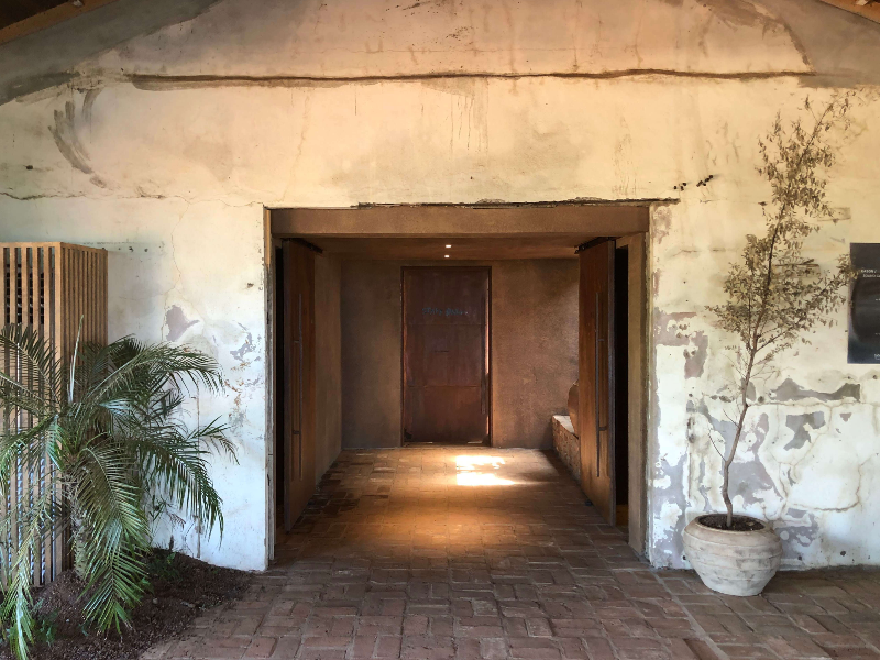 제주인스밀 내부 - 벽이 오래된 느낌이 나고 문을 중심으로 양쪽에 화분이 놓여있다