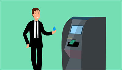 ATM 기계 앞에 카드를 들고 서 있는 남자