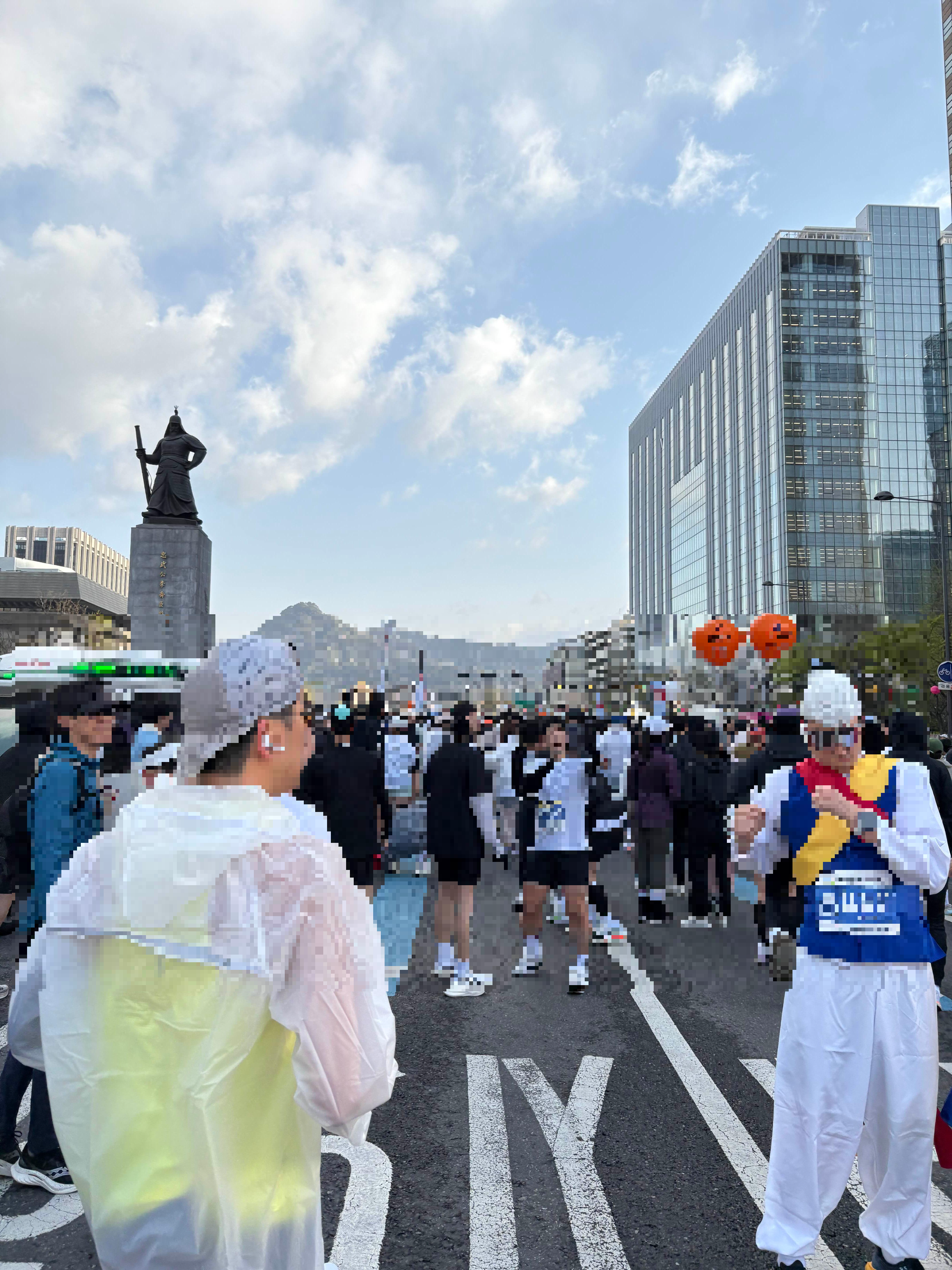 alt=&quot;맑은 하늘 아래 서울 광화문 광장에서 마라톤을 준비하는 러너들의 군중과 도심 풍경&quot;