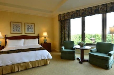 클래식한 느낌으로 인테리어 되어 있는 호텔 객실&#44; 침대와 소파등이 놓여져 있다.