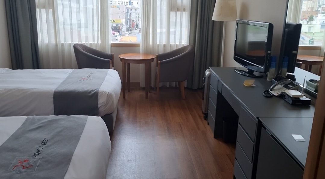 홈포레스트-호텔-객실에-침대2개와-테이블-그리고-의자가-놓여있다