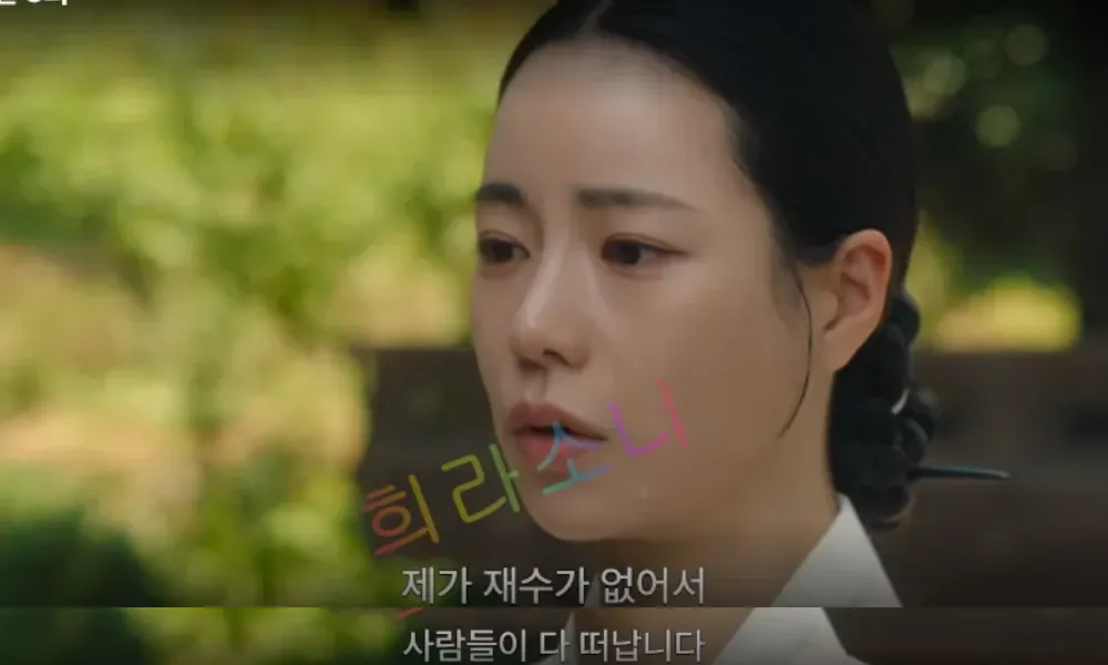 태영이 한복을 입고 머리를 뒤로 단정히 묶은 채&amp;#44; 약간 슬픈 표정으로 화면을 바라보고 있다. 뒤 배경에는 푸른 자연 풍경이 어렴풋이 보이며&amp;#44; 화면 하단 자막에는 &amp;quot;제가 재수가 없어서 사람들이 다 떠납니다&amp;quot;라고 적혀 있다. 