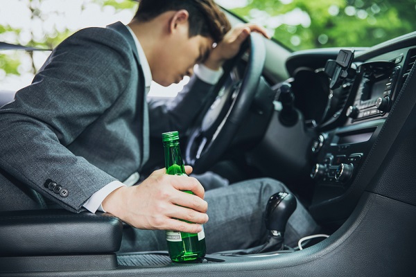 음주운전자가 술병을 쥐고 운전석에서 슬퍼하고 있는 사진