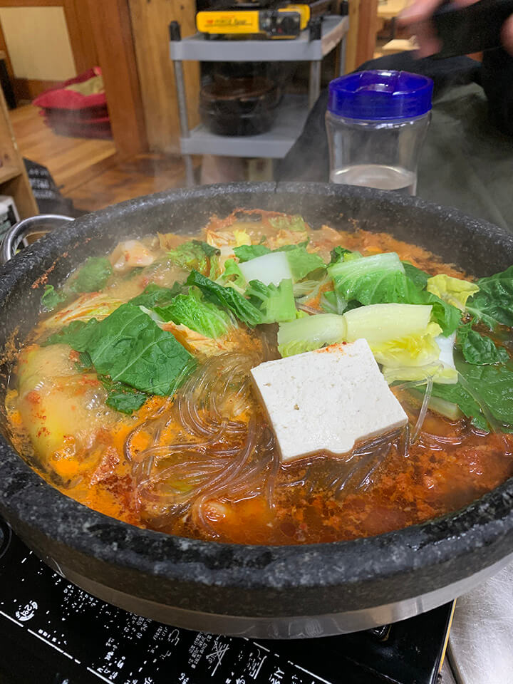 굉장 오랜 세월을 보낸 것 같은 무쇠팬에 자글자글 끓고 있는 곱창전골의 모습.