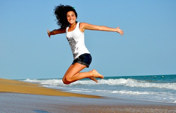 해변에서 제자리 점프를 하는 여성 사진