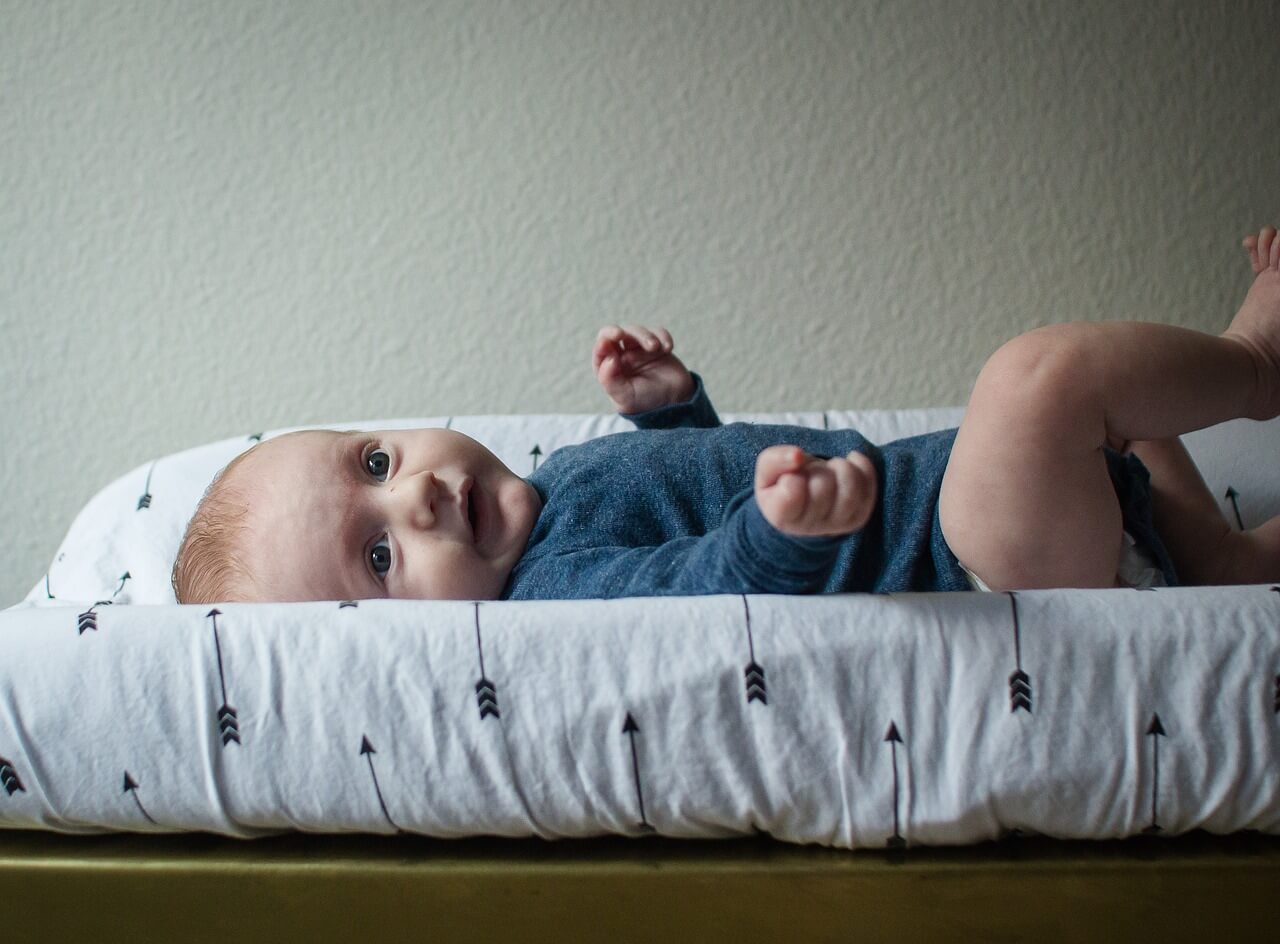 침대 위에 누워있는 파란색 옷을 입고 있는 아기