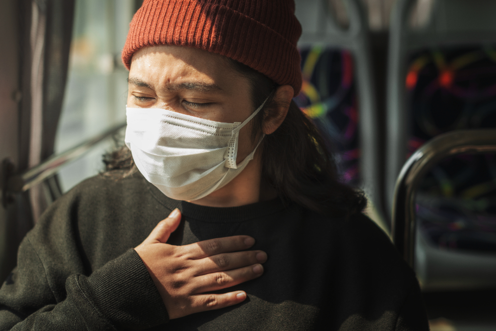 마스크를 쓰고 오른손을 가슴 위에 올린 채 인상을 찡그리고 있는 남자