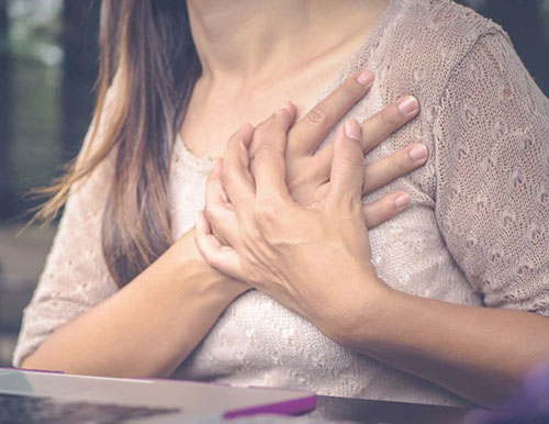 폐경 증상인 가슴의 떨림으로 인해 가슴을 잡고 있는 중년 여성