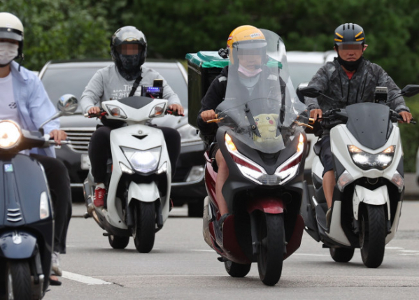 배달을 하는 오토바이들의 도로 위 사진이다.