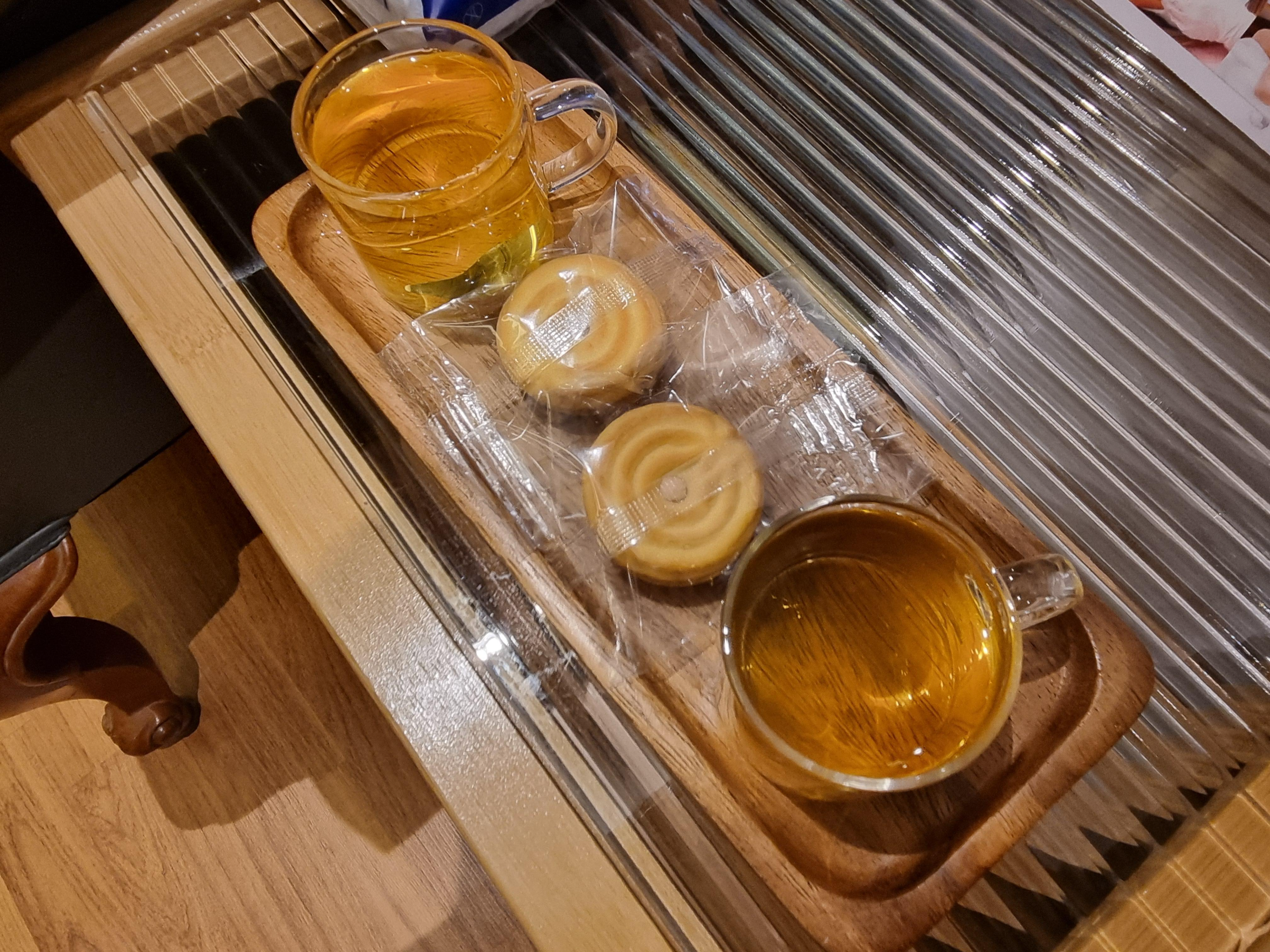작은 유리잔에 담긴 차와 개별 포장된 다과