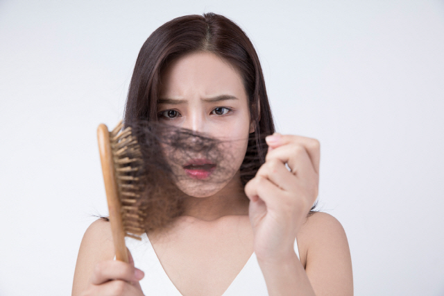 여성이 빗질하다 빠진 머리카락보고 놀라는 사진