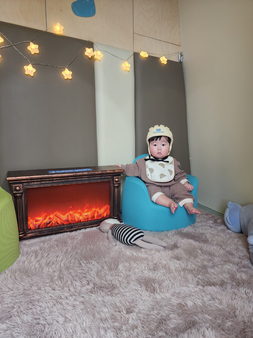 아기 헬멧을 쓰고 의자에 앉아있는 6개월 아기 사진.