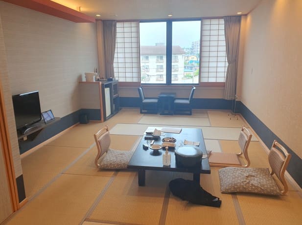 일본식 타다미 위에 검은색 좌식 테이블이 있고 그 옆으로 좌식 의자가 있다