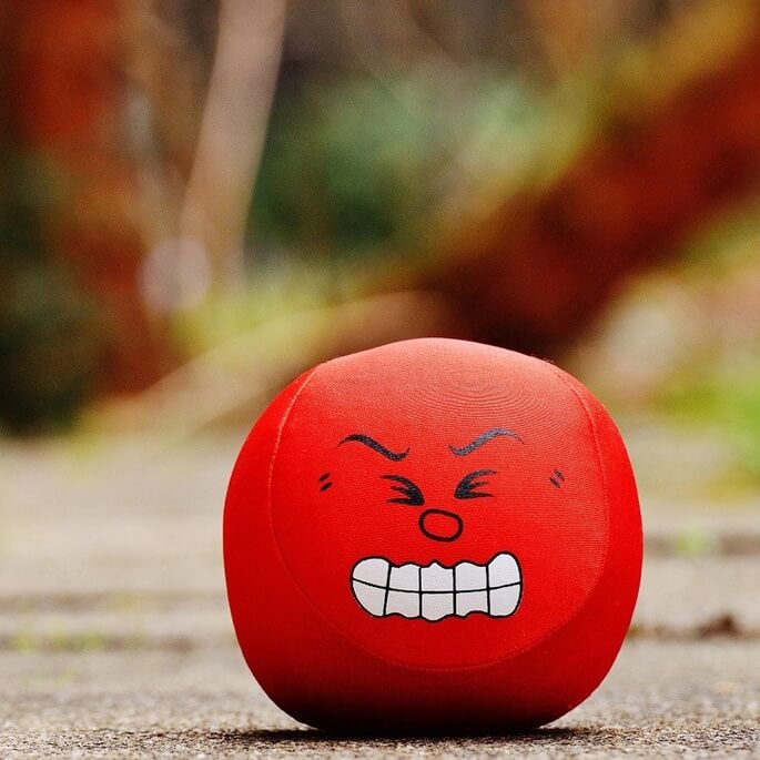찡그린 얼굴 표정이 그려져있는 빨간 공이 바닥에 놓여져있는 모습