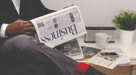 이 사진은 중년의 정장을 입은 사람이 비즈니스 신문을 앉아서 보고 있는 사진