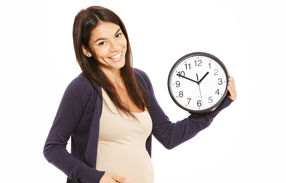 임신한 여성이 시계를 들고 웃고있는 모습