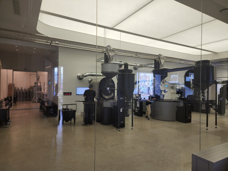 유리 벽 너머에 있는 엄청나게 큰 커피 로스팅 기계들.