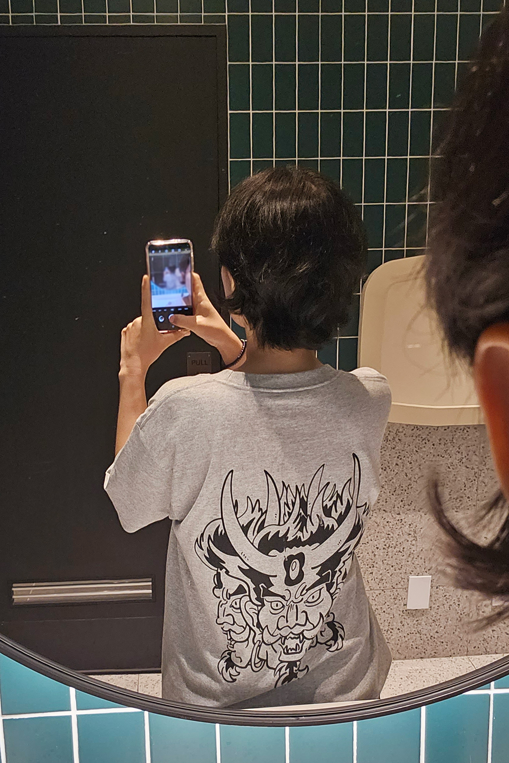 아수라 그림이 그려진 회색 티셔츠 뒷면을 거울에 대고 찍음