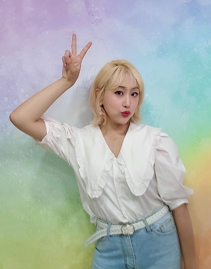 손가락브이를하고있는-블라우스를입은여성의모습