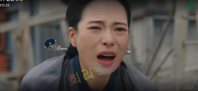 검은색 상의를 입고 단정히 묶은 머리를 태영이 울먹이며 서방님을 부르고 있다. 배경에는 허물어진 건축물이 보인다. 자막 없음. 