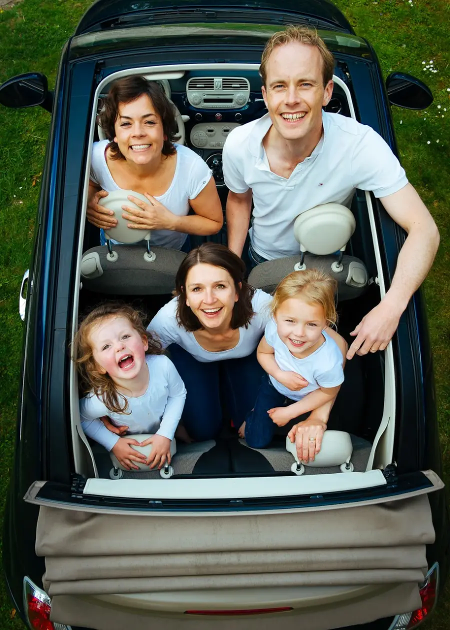 초록 잔디 위 자동차 뚜겅이 열린 상태에서 엄마아빠 아이들을 하늘을 보며 웃고있는 모습