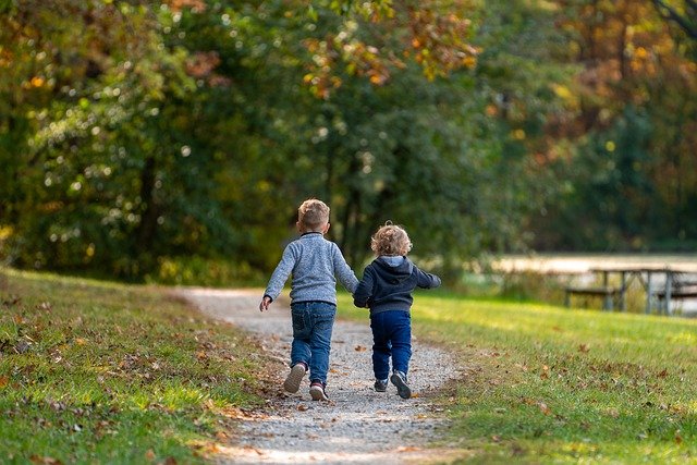 두 형제가 손을 잡고 공원에서 뛰고 있다.