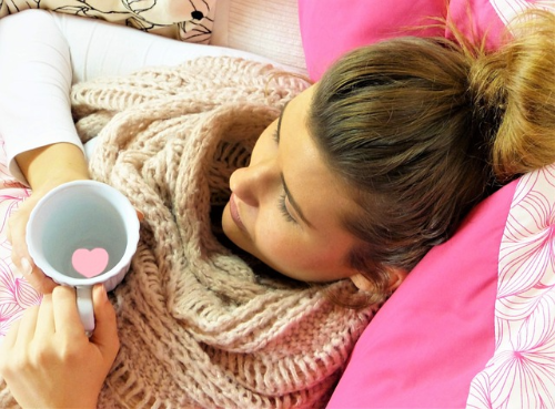 한 여성이 컵을 들고 편하게 누워있는 사진