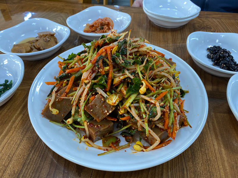 콩나물 ,  당근 ,  미나리 ,  붉게 물든 도토리묵을 접시에 담는다