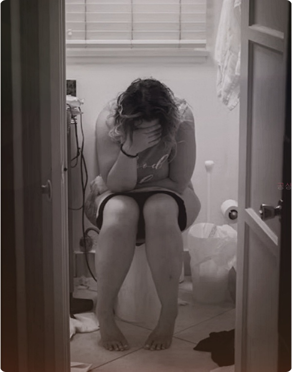 화장실 변기 위에 앉아서 슬픔에 힘겨워 하는 여성