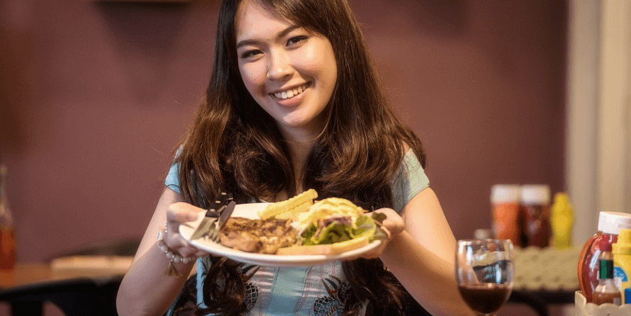 단백질 음식이 들어 있는 접시를 들고 웃고 있는 여성