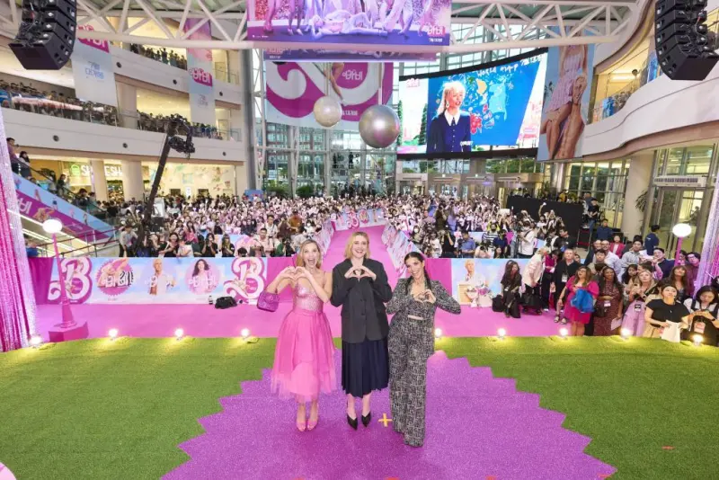 핑크색 드레스와 금발의 마고 로비와 아메리카 페레라&#44; 그레타 거윅 감독이 하트를 손으로 표현하면서 단체 사진을 찍고 있는 바비 영화 내한 시사회