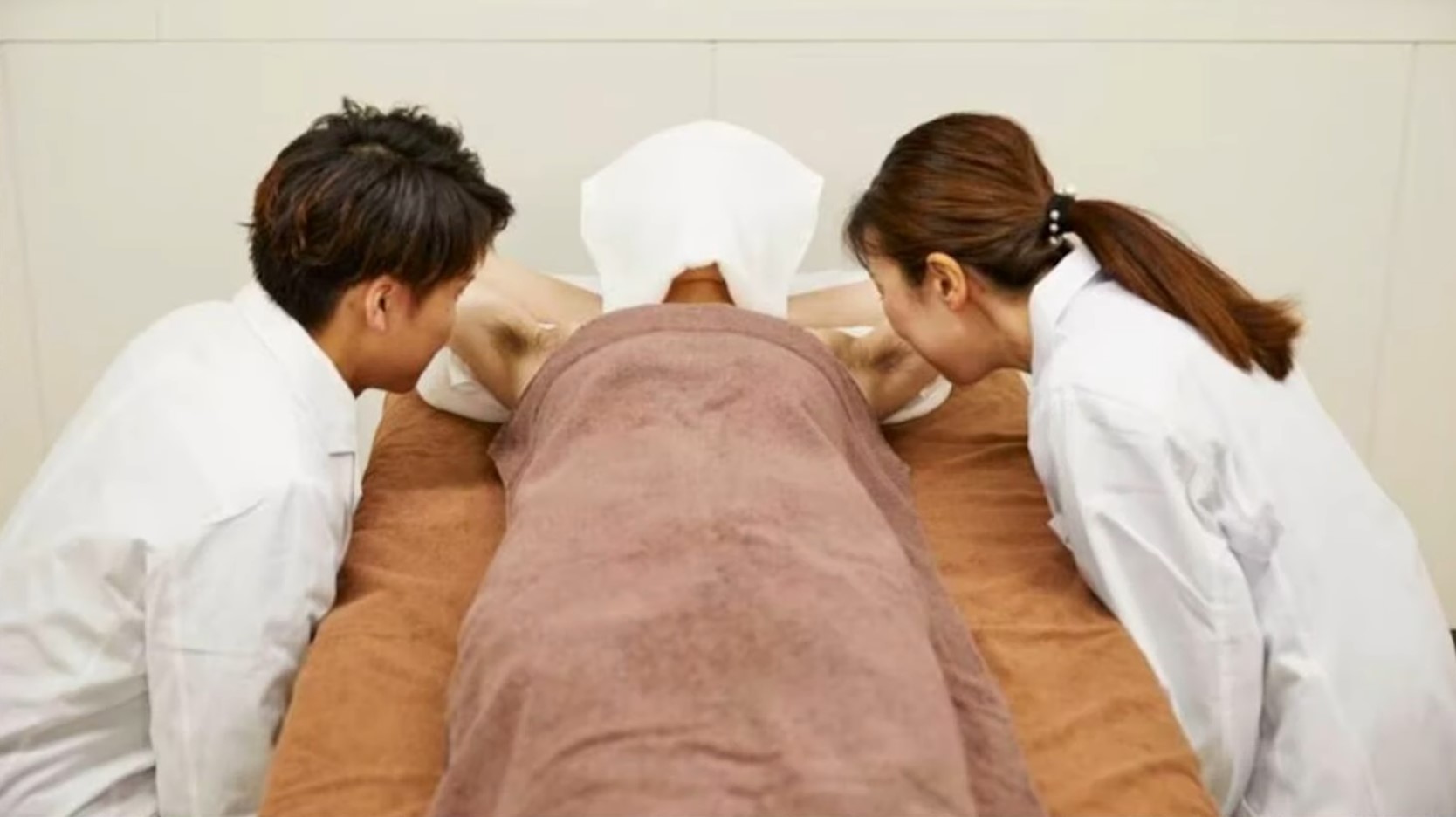 겨드랑이 감별사 남자와 여자가 실험자 양 옆에 앉아 겨드랑이 한 쪽씩 냄새를 맡고 있다.