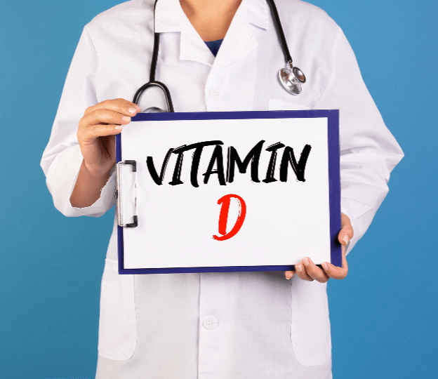 의사가운을 입고 청진기를 목에 맨 사람이 Vitamin D 라고 적힌 팻말을 들고 서 있는 모습