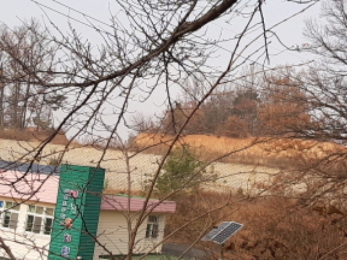 인천지방법원2022타경13454 본건 전경(학교 뒤 축대 윗쪽과 산봉우리 사이에 위치)